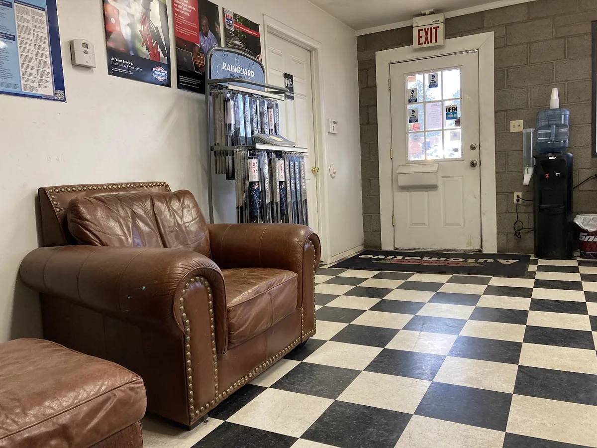 The remodelled front office, with a leather armchair, a black and white tiled floor and a parts display along the wall.
